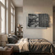 Strialux Mono Illusion Grey Leather & Acrylic 3D Wall Art with black and white striped relief on a grey base, mounted above a bed in a sunlit bedroom.