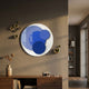 Cirelo Sky & Cobalt Disc Acrylic 3D Wall Art mounted above a wooden sideboard, flanked by gold metal spheres on a warm beige wall in a modern hallway.
