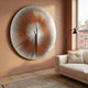 Lustara Copper Gradient Circular Leather 3D Wall Art by Giant Sculptures displayed on a terracotta wall above a cream sofa beside a black floor lamp and window.