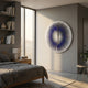 Lustara Violet Gradient Circular Leather 3D Wall Art by Giant Sculptures mounted in a modern bedroom with grey walls, wood bed, and bookshelf by a window.