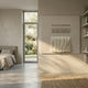 Textura Tiered Linen Fringe 3D Wall Art by Giant Sculptures mounted in a sunlit beige bedroom with concrete floor, jute rug, bed, and garden door nearby.