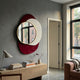 Solistra Crimson I Layered Round Mirror 3D Wall Art by Giant Sculptures, with gold-framed mirror over crimson and white shapes, above a wooden console in a grey room.