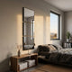Quadria 3-Panel Square Wall Mirror by Giant Sculptures mounted vertically in a minimalist bedroom above a walnut console beside a linen-dressed bed and window.
