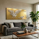 Aurellion Soaring Eagle & Birds Gold Panel 3D Button Wall Art by Giant Sculptures displayed above a grey velvet sofa in a living room with a walnut coffee table and fiddle leaf fig plant.