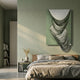Arvinea Green Flow Sculptural Leather 3D Wall Art by Giant Sculptures with draped metallic ribbons displayed above a wooden bed in a sage green bedroom.
