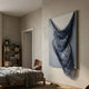 Arvinea Blue Flow Sculptural Leather 3D Wall Art by Giant Sculptures, with cascading navy and frost white leather strips, displayed on a bedroom wall beside a leather chair.