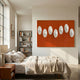 Virello Terracotta & White Disc Leather 3D Wall Art by Giant Sculptures mounted above a linen-dressed bed beside a bookshelf and wooden nightstand in a sunlit bedroom.