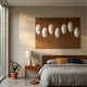 Virello Mocha & White Disc Leather 3D Wall Art by Giant Sculptures mounted above a walnut bed and nightstand in a sunlit modern bedroom with rubber plant.