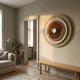 Radiora Copper & Gold Leather Circular 3D Wall Art by Giant Sculptures mounted in a neutral living room above a wooden bench, beside a linen sofa and potted plant.