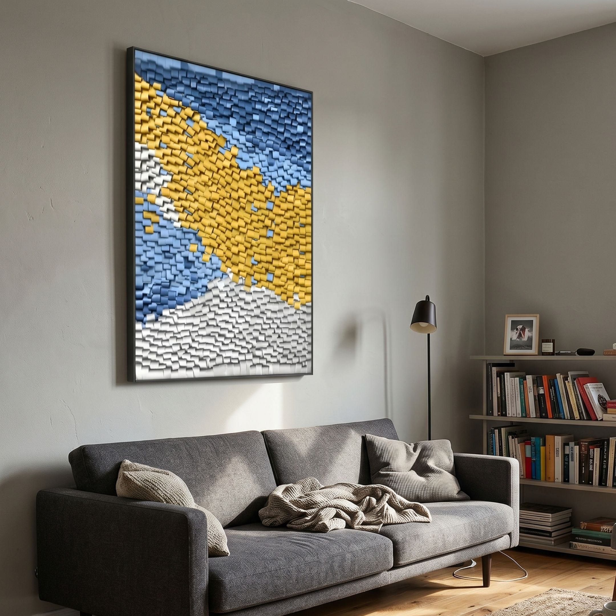 Tilora I Abstract Folded Leather 3D Wall Art by Giant Sculptures in mustard, sky blue, and white diagonal bands, hung above a grey sofa beside a bookshelf.