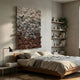Liora Brown Ombre Ribbon Leather 3D Wall Art by Giant Sculptures mounted above a wooden bed in a neutral bedroom with linen bedding and shelving alcove.