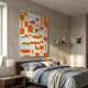 Moduvo Orange & White Geometric 3D Carving Wall Art by Giant Sculptures mounted above a wooden bed with blue and beige linens in a modern bedroom.