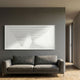 Varelo Horizontal Geometric Relief 3D Wall Art in white, mounted on a grey wall above a charcoal sofa in a modern living room with wood flooring.