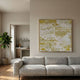 Orienta II Templescape Gold 3D Carving Wall Art by Giant Sculptures displayed above a grey sofa in a minimalist living room with a fiddle leaf fig and kitchen view.