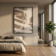 Deralin Mocha Flow Abstract 3D Carving Wall Art in a black frame, displayed above a linen-dressed bed in a sunlit bedroom with a fiddle leaf fig by the window.