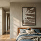 Deralin Mocha Drift Abstract 3D Carving Wall Art in a black frame above a wood-headboard bed with blue linen, mounted on a cream wall beside a hallway.