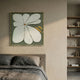 Petala Green & White Bloom Wood Relief 3D Wall Art by Giant Sculptures displayed above a linen-dressed bed in a warm bedroom beside open wooden shelving.