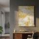 Noyari City Rhythms 3D Carving Wall Art in a gold frame, displaying a white sandstone abstract cityscape on gold, hung above a walnut desk in a modern office.