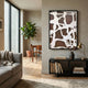 Drosan Earth Trace III Wood Carving 3D Wall Art with white organic shapes on brown wood in a slim black frame, mounted above a console in a modern living room.