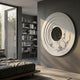 Aethera Silver Leaves Round Wood Carving 3D Wall Art by Giant Sculptures mounted on a grey bedroom wall beside a window, bed, and study nook with shelves.