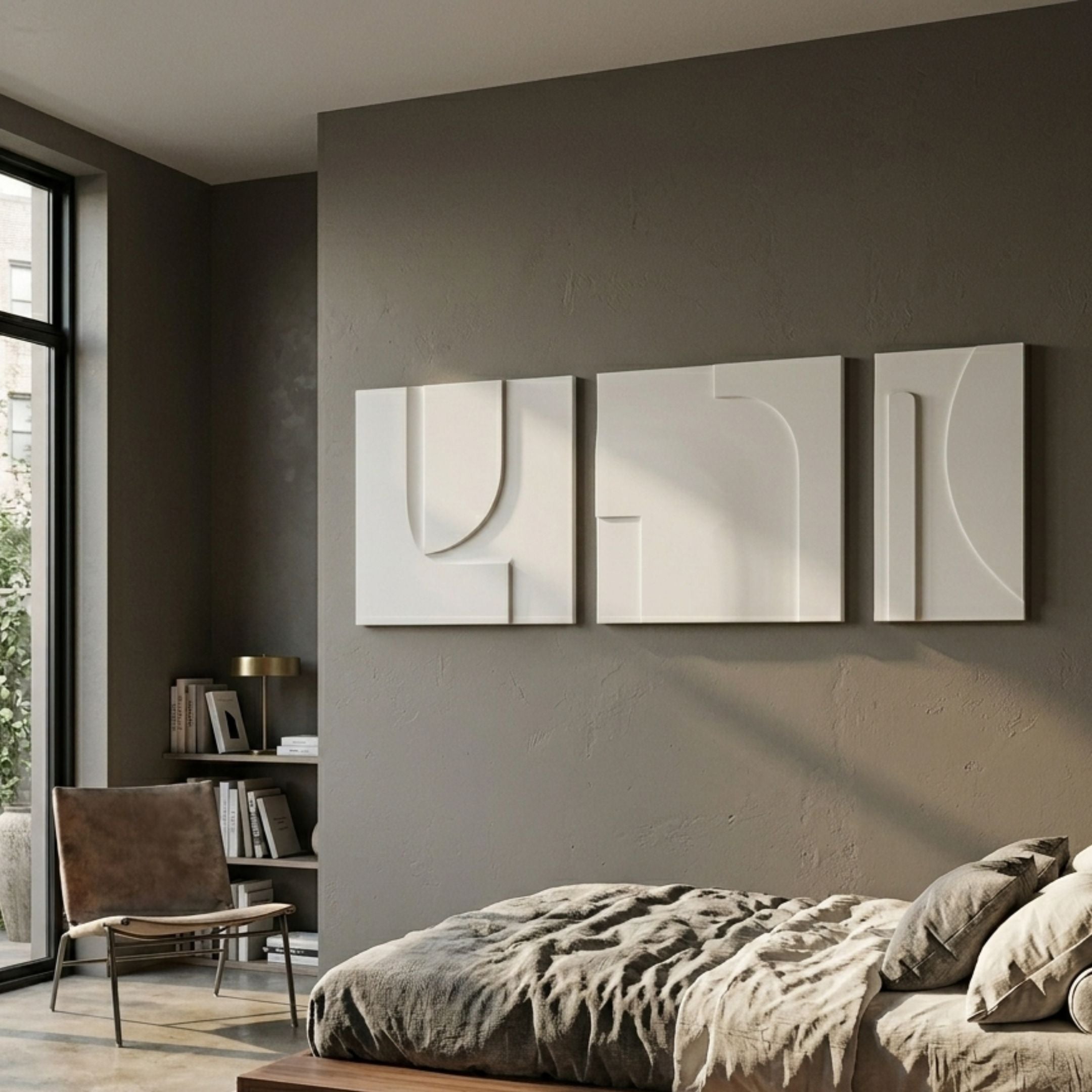 Moro II Triptych White Relief 3D Wall Art by Giant Sculptures displayed above a linen-dressed bed in a warm grey bedroom with a leather chair and bookshelf nearby.
