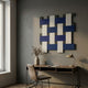 Tressel Interlock Blue Oil Painting 3D Wall Art by Giant Sculptures, with woven navy, white, and grey rectangles displayed above a wooden desk and chair.