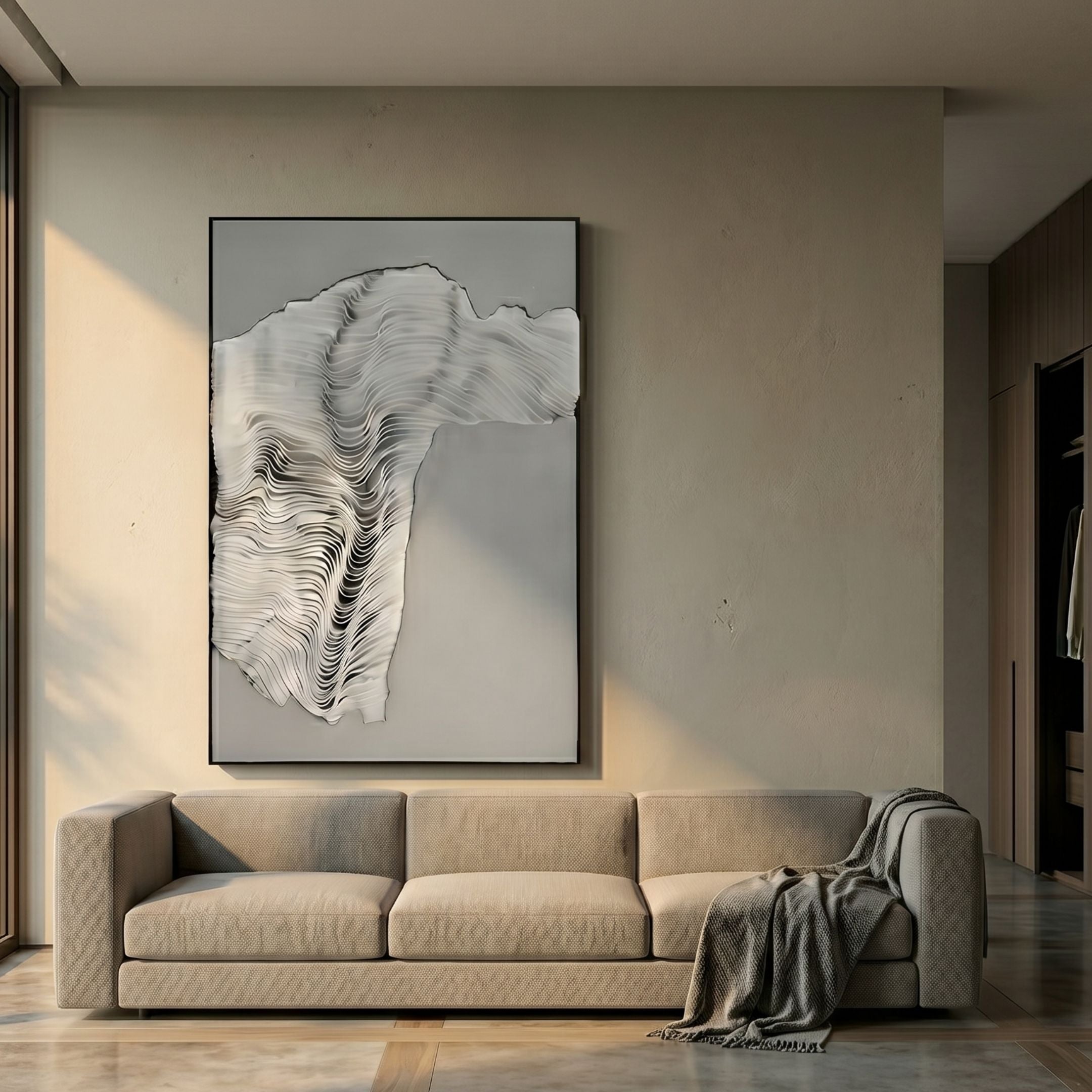 Ravelle Grey Contour Felt 3D Relief Wall Art by Giant Sculptures in a black frame, displayed above a beige sofa with a grey throw in a sunlit living room.