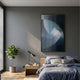 Cyclastra Blue Optical Spiral Acrylic 3D Wall Art by Giant Sculptures mounted above a wooden nightstand in a grey bedroom with blue linen bedding and a fiddle-leaf fig.
