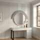 A modern vanity with a white top and black legs stands by a paneled wall. Above it hangs the Arcaluna Sky & Mint Layered Round Mirror 3D Wall Art by Giant Sculptures, framed in pastels. A vase with dried flowers sits on the sunlit tabletop.