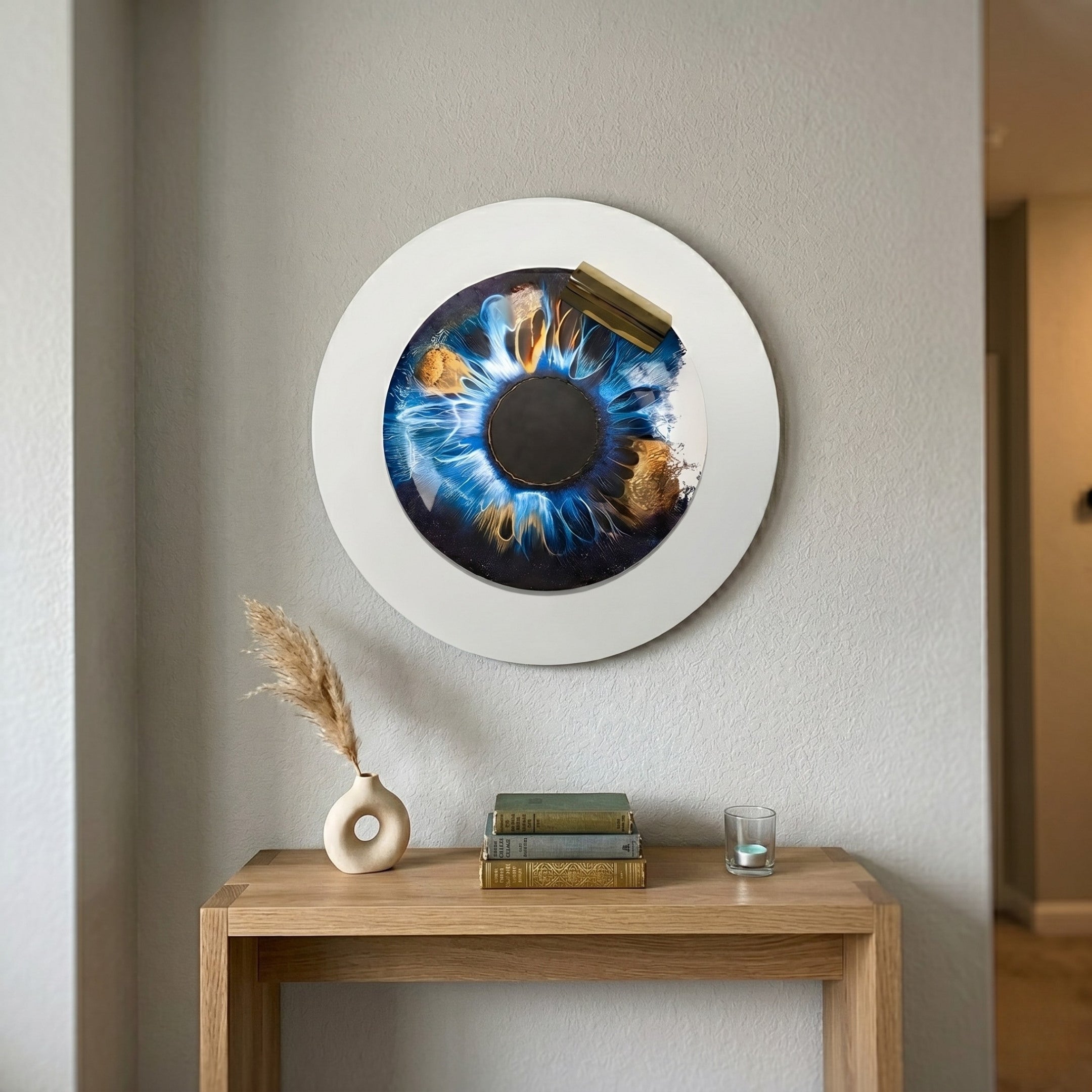 A minimalist wooden console with a vase, books, and candle sits below the Iriselle Cosmic Blue Crystal Porcelain Round 3D Wall Art by Giant Sculptures—an eye-catching designer piece—mounted on a light gray wall.