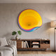 Rippletone Sunset Dive Gradient Acrylic UV 3D Wall Art by Giant Sculptures, with yellow, pink and blue rippled rings, mounted above a walnut sideboard in a living room.