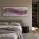 Harmoni Pink Gradient Wave Acrylic 3D Wall Art in a gold frame above an upholstered bed with linen bedding, beside a ribbed black side table.