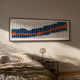 Waveform I Dual Motion Acrylic 3D Wall Art by Giant Sculptures in indigo, white, and orange, mounted above a bed with a bedside lamp in a sunlit bedroom.