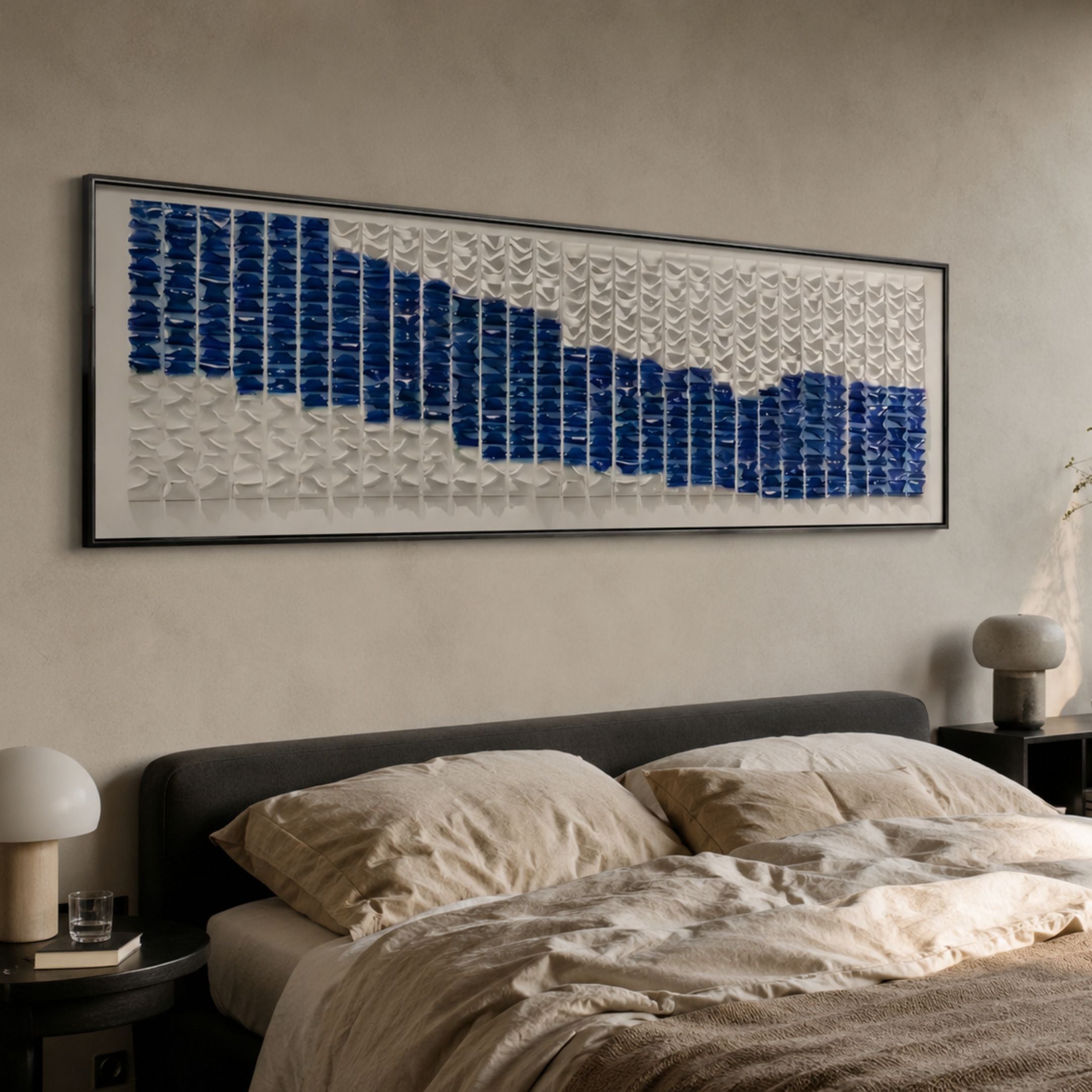 Waveform Indigo Horizon Acrylic 3D Wall Art by Giant Sculptures mounted above a grey upholstered bed with linen bedding, showing indigo and white tiled wave rhythm.