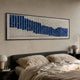 Waveform Indigo Horizon Acrylic 3D Wall Art by Giant Sculptures mounted above a grey upholstered bed with linen bedding, showing indigo and white tiled wave rhythm.