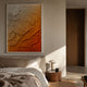 Petalwave Amber Fade Layered Bloom Leather 3D Wall Art in white frame above a linen bed, beside a wooden nightstand with lamp in a warm bedroom.