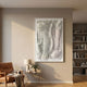 Contour Stone Grey Fluid Terrain Lines Felt 3D Wall Art by Giant Sculptures, framed above a side table with lamp and plant beside a tan leather armchair.