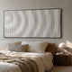 Luna II Spiral Illusion Flow Acrylic 3D Wall Art by Giant Sculptures, white vertical ridges in a slim dark frame, mounted above a linen-dressed bed with bedside lamp.