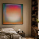 Lumin Ethereal Light Flood Crystal Porcelain Wall Art with peach, pink and aqua gradient in a slim dark frame, displayed above a bed beside a bookshelf.
