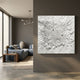Velorra Pearl White Bloom Ribbon Frameless 3D Wall Art by Giant Sculptures mounted on a grey wall beside a modern living room with blue sofa and vase.
