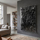 Metallique Deep Black Crinkle Texture Leather 3D Wall Art by Giant Sculptures mounted on a grey wall in a modern living room with linen sofa and bookshelf.
