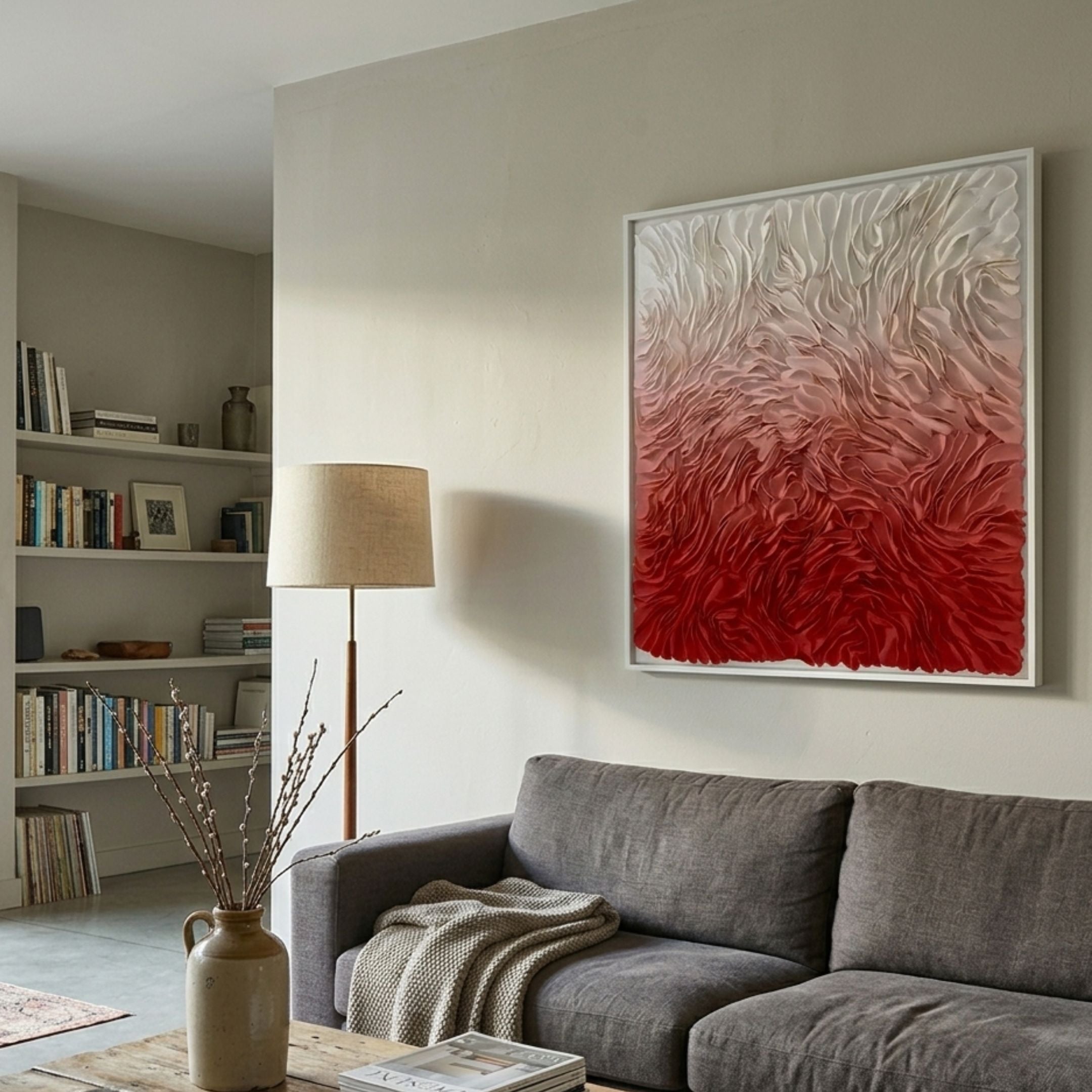 Floravia White & Scarlet Red Ombre Leather 3D Wall Art by Giant Sculptures displayed above a grey sofa in a living room with a floor lamp and bookshelves.