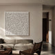 Bloom White Curved Petal Acrylic 3D Wall Art by Giant Sculptures displayed above a taupe sofa in a neutral living room with wooden cane chair and coffee table.