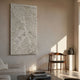 Vermira Ivory I Textured Leather 3D Metal Framed Wall Art by Giant Sculptures mounted in a sunlit neutral living room beside a wooden chair and dark vase.