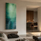 Aquavue Teal & Emerald Gradient Acrylic 3D Wall Art mounted in a modern living room above a linen sofa, with a wood-furnished dining area visible beyond.