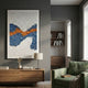 Wave Cobalt Blue & Rust Orange Acrylic 3D Wall Art in a black frame above a wooden console with lamp, beside a green armchair in a grey living room.