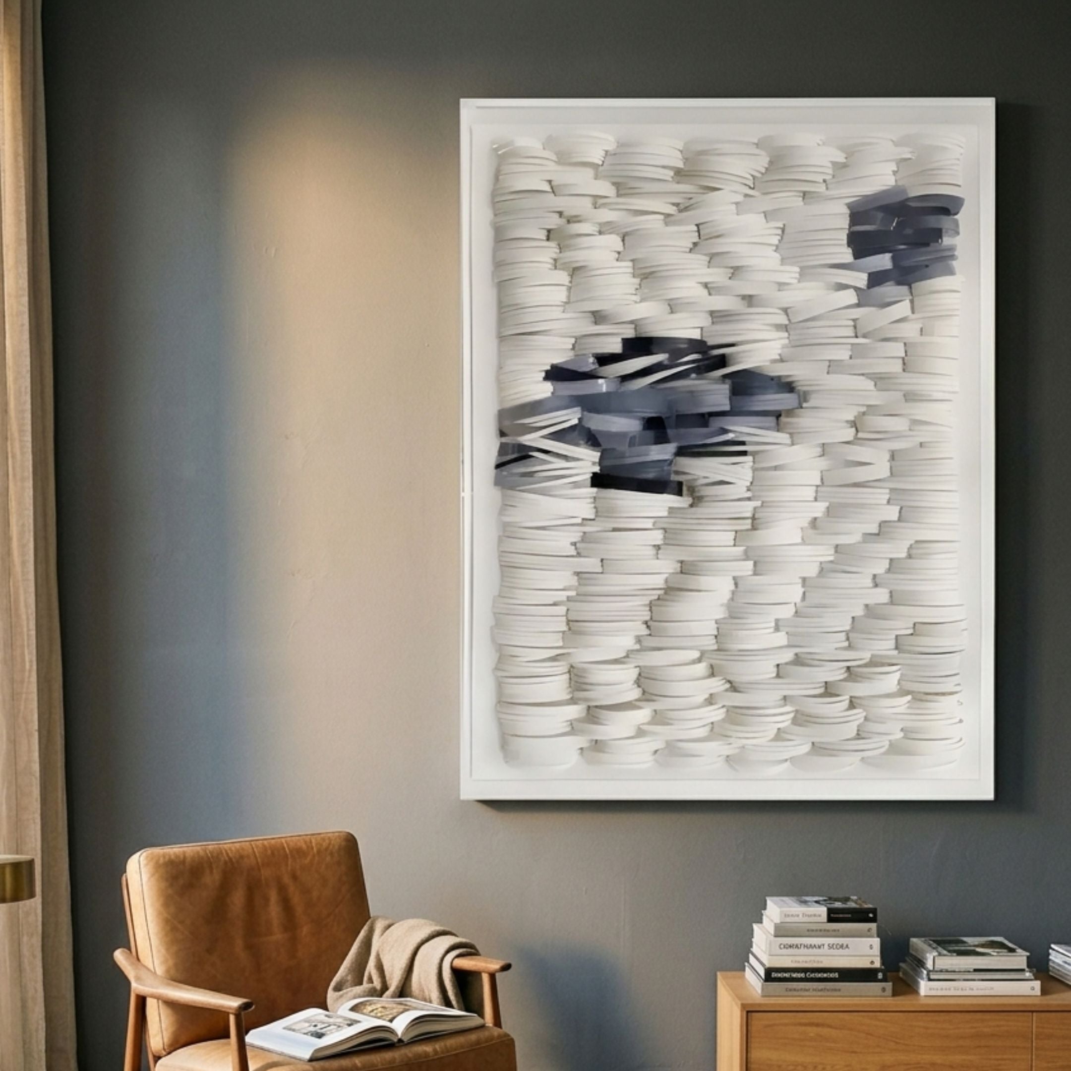 Monovista Frost White & Ocean Blue Acrylic Box 3D Paper Wall Art by Giant Sculptures displayed above a tan leather chair and wooden side table with books.