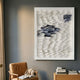 Monovista Frost White & Ocean Blue Acrylic Box 3D Paper Wall Art by Giant Sculptures displayed above a tan leather chair and wooden side table with books.