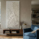 Vermira Ivory I Textured Leather 3D Wall Art by Giant Sculptures mounted above a walnut console in a living room with a blue armchair and bookshelves.