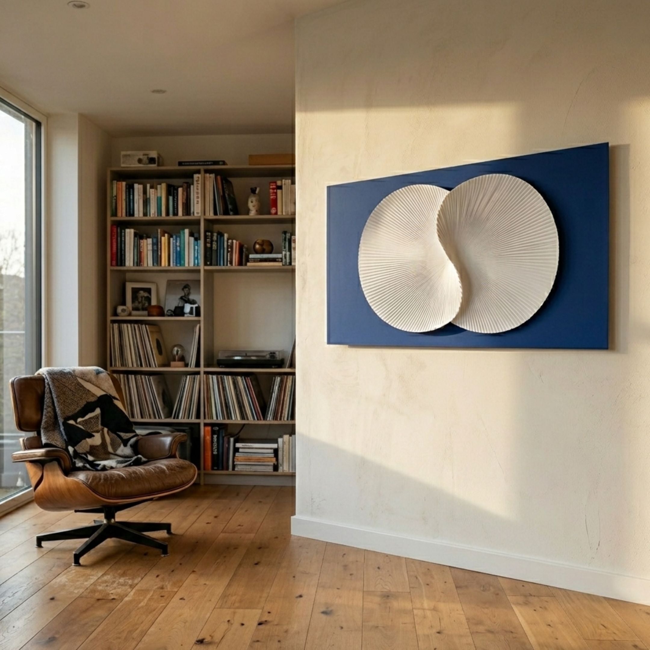 Artivio Blue & White Wood Relief 3D Wall Art by Giant Sculptures displayed in a sunlit modern living room beside a leather lounge chair and bookshelf.